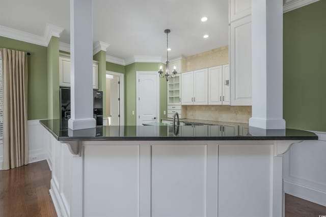 kitchen with a kitchen bar, decorative light fixtures, white cabinetry, and ornamental molding