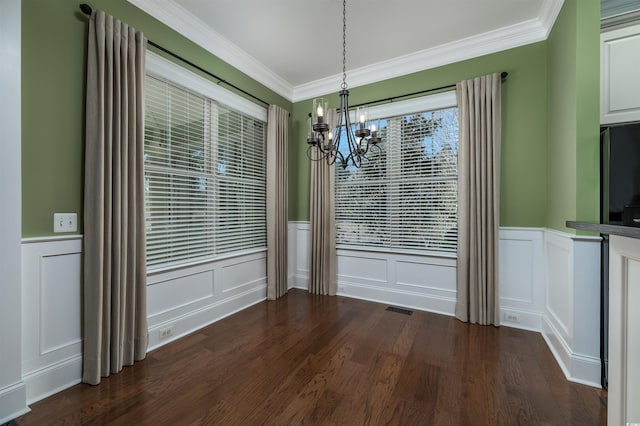 unfurnished dining area with dark hardwood / wood-style floors, crown molding, and a chandelier