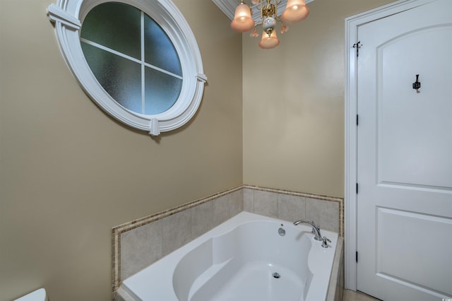 bathroom with a chandelier, ornamental molding, and tiled tub