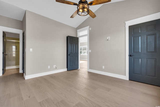 unfurnished bedroom with ensuite bath, light wood finished floors, baseboards, and high vaulted ceiling