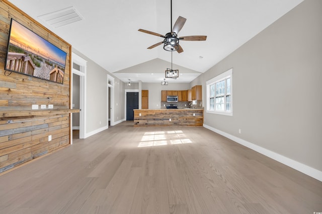 unfurnished living room featuring baseboards, visible vents, a ceiling fan, light wood-style flooring, and vaulted ceiling