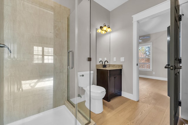 bathroom featuring toilet, wood finished floors, vanity, baseboards, and a shower stall