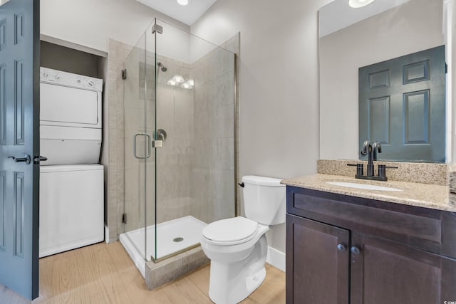 bathroom featuring a stall shower, stacked washer / drying machine, vanity, and wood finished floors