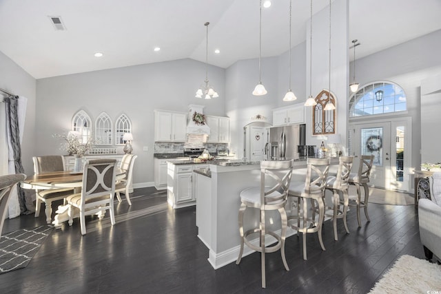 kitchen featuring decorative backsplash, stainless steel refrigerator with ice dispenser, decorative light fixtures, high vaulted ceiling, and white cabinetry