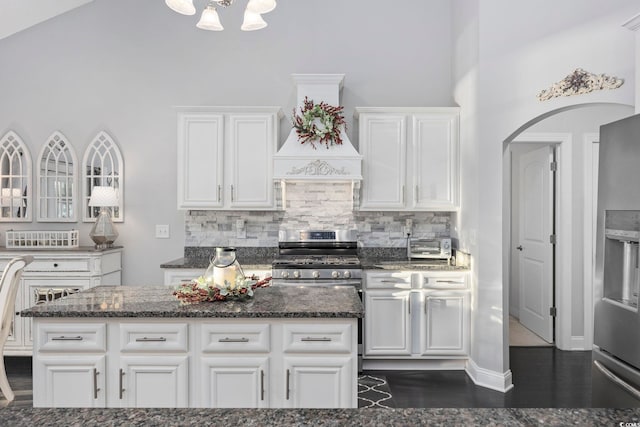 kitchen featuring white cabinets, backsplash, stainless steel appliances, and dark stone counters