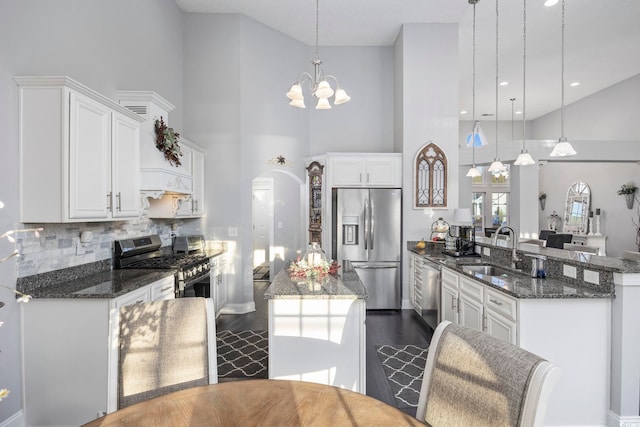 kitchen featuring white cabinets, a high ceiling, decorative light fixtures, and appliances with stainless steel finishes