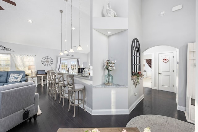 interior space featuring pendant lighting, a kitchen breakfast bar, dark wood-type flooring, and a high ceiling