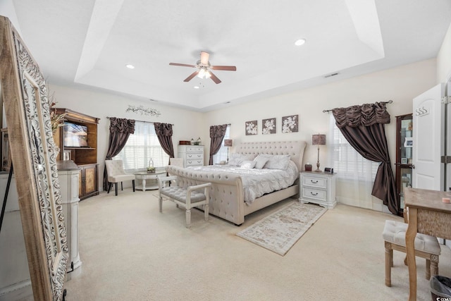 carpeted bedroom featuring a tray ceiling and ceiling fan