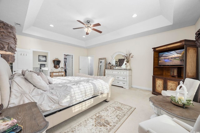 carpeted bedroom with a tray ceiling and ceiling fan