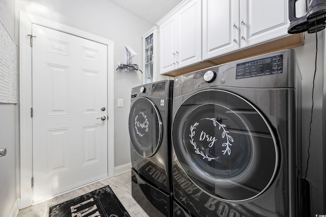 washroom with cabinets and washing machine and clothes dryer