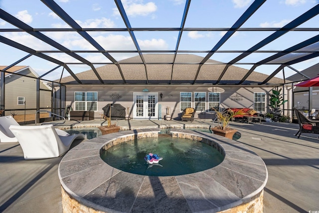 view of swimming pool with glass enclosure, an in ground hot tub, french doors, and a patio