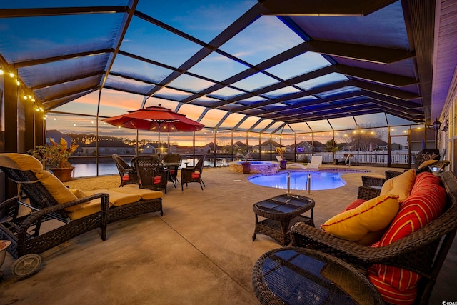 patio terrace at dusk featuring a swimming pool with hot tub, an outdoor living space, a water view, and a lanai