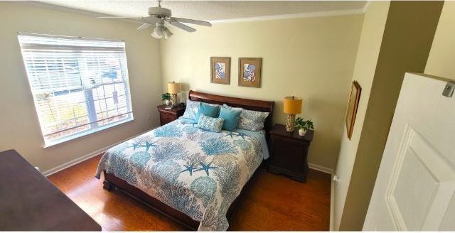 bedroom with ceiling fan, dark hardwood / wood-style flooring, and multiple windows