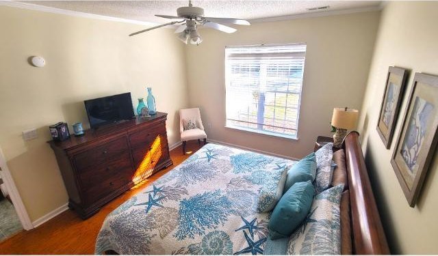 bedroom featuring ceiling fan, crown molding, and wood-type flooring