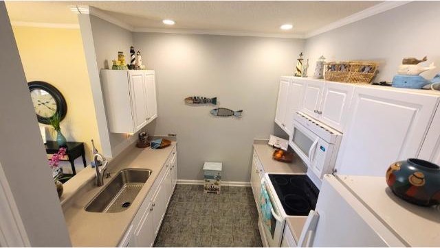 kitchen featuring white appliances, white cabinetry, ornamental molding, and sink