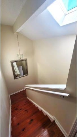 stairway with a skylight and hardwood / wood-style flooring