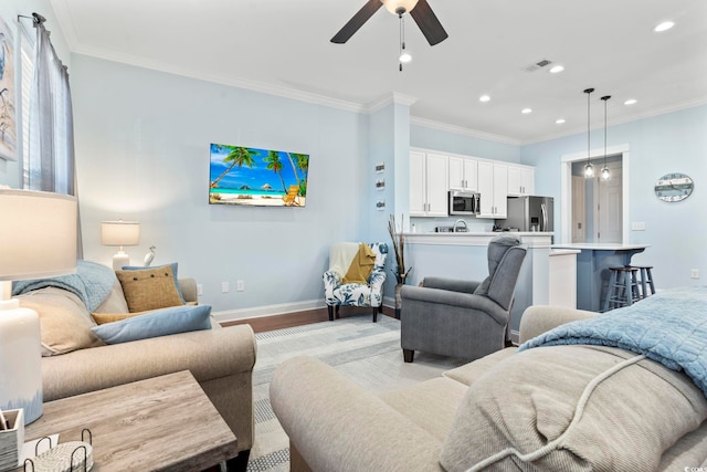 living room with ceiling fan, ornamental molding, and light hardwood / wood-style flooring