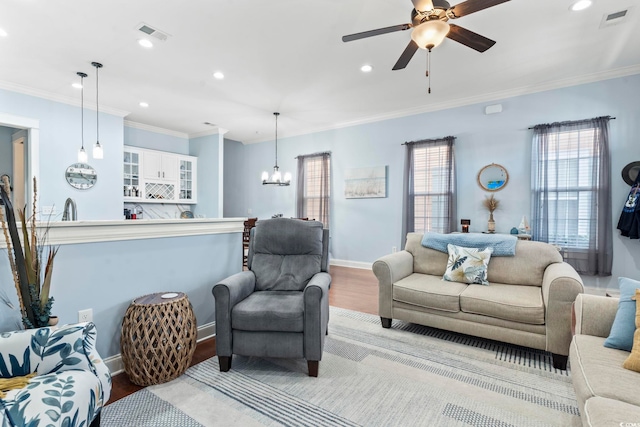 living room with crown molding, light hardwood / wood-style flooring, and ceiling fan with notable chandelier