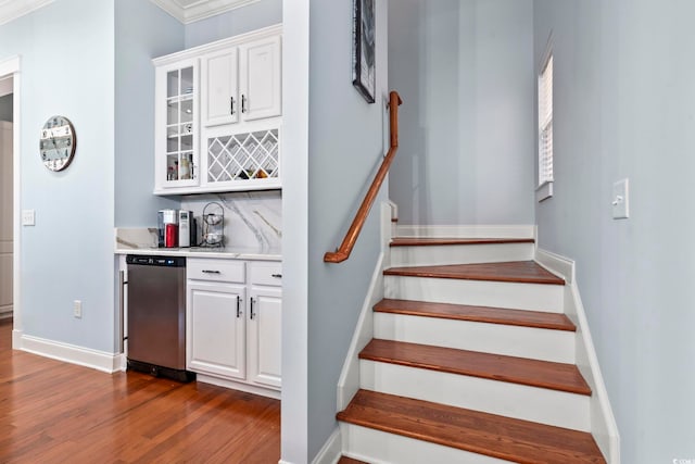 staircase featuring crown molding, hardwood / wood-style floors, and indoor bar