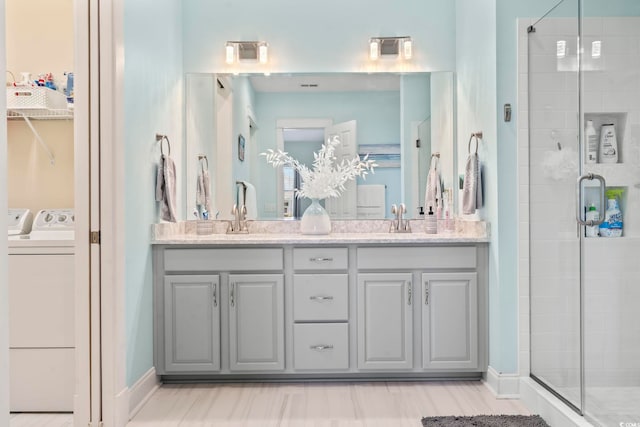 bathroom featuring vanity, washer and clothes dryer, and a shower with shower door