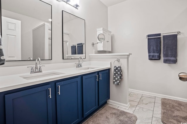 full bath with a sink, baseboards, double vanity, and marble finish floor