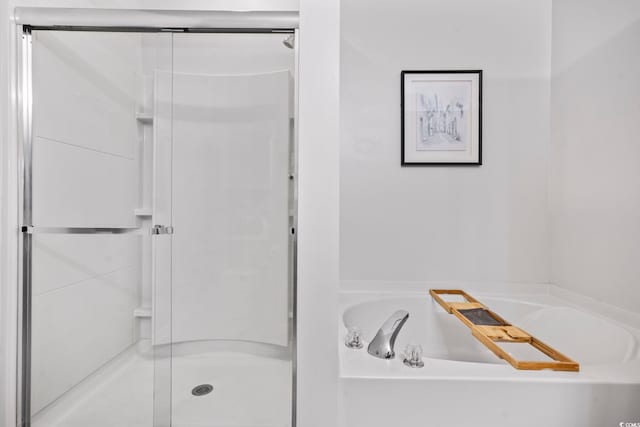 full bathroom featuring a shower stall and a bath