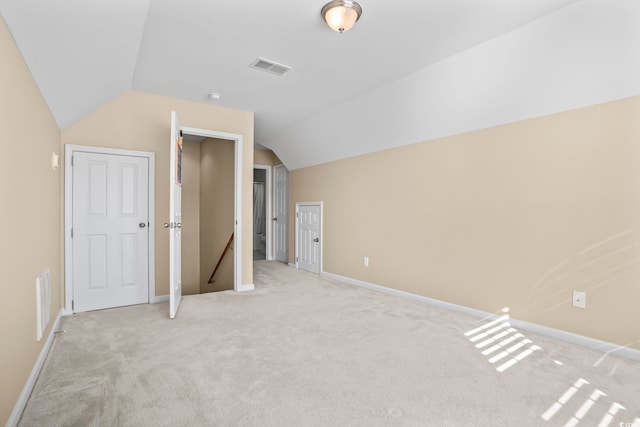 unfurnished bedroom featuring visible vents, light colored carpet, baseboards, and lofted ceiling