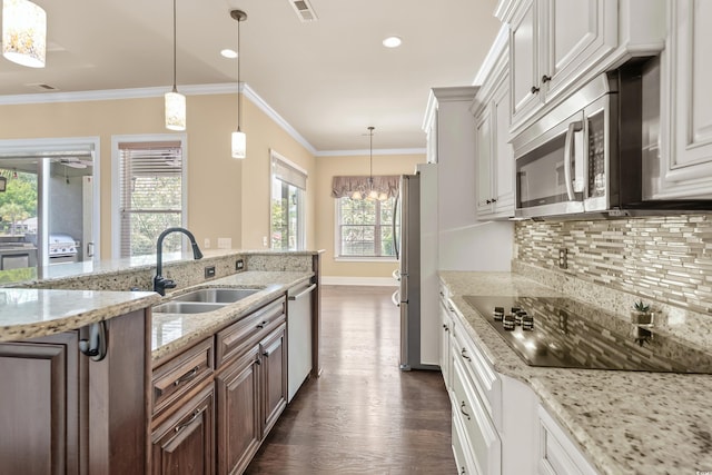 kitchen with stainless steel appliances, sink, decorative light fixtures, an inviting chandelier, and white cabinets