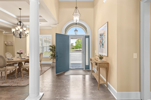 entryway featuring plenty of natural light, an inviting chandelier, ornamental molding, and decorative columns