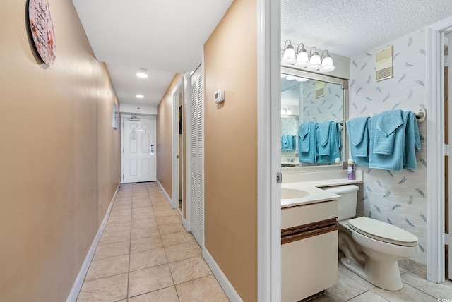 hallway with a textured ceiling and light tile patterned flooring