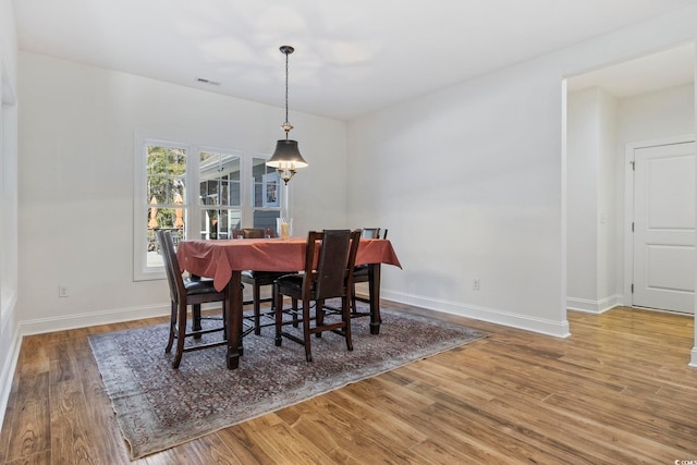 dining area with wood finished floors, visible vents, and baseboards