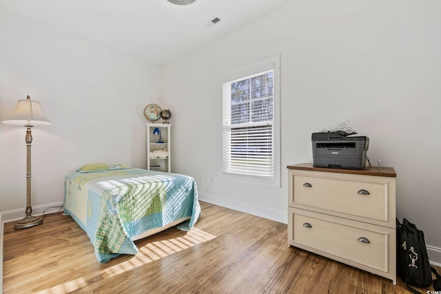 bedroom with baseboards, visible vents, and light wood finished floors