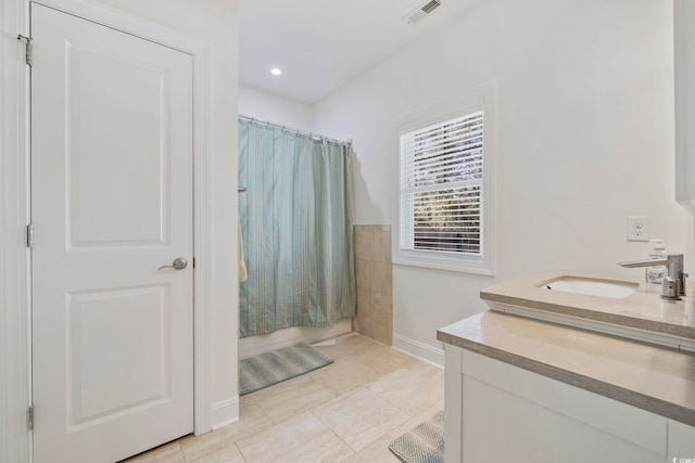 bathroom featuring visible vents, baseboards, tile patterned floors, shower / bathtub combination with curtain, and vanity