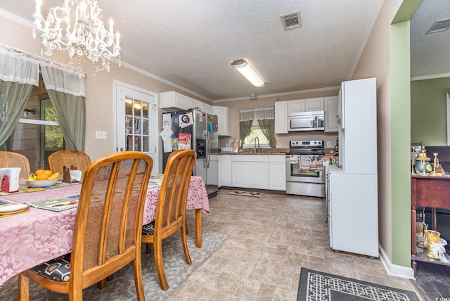 dining area featuring crown molding, sink, a textured ceiling, and an inviting chandelier