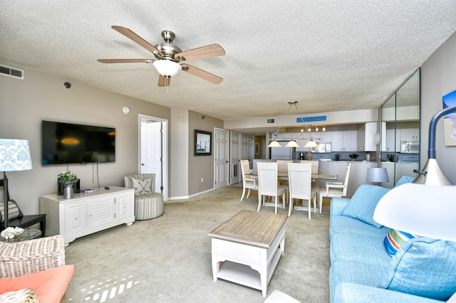 carpeted living room featuring ceiling fan and a textured ceiling