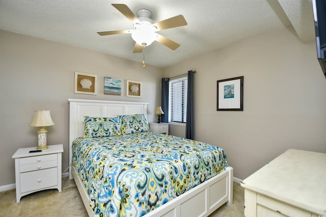 bedroom featuring a textured ceiling, light colored carpet, and ceiling fan