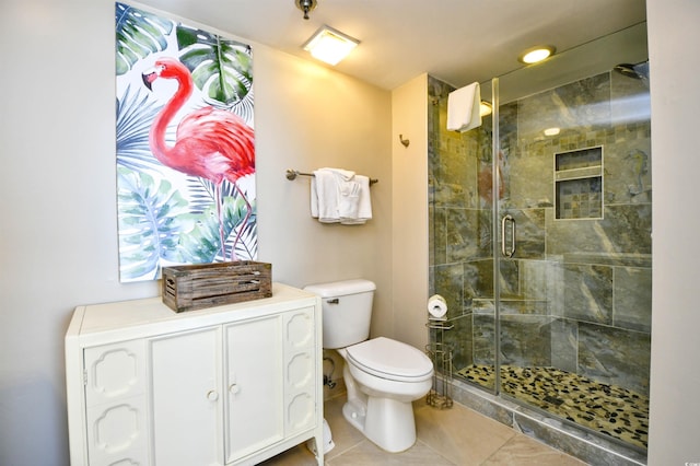 bathroom with tile patterned flooring, toilet, and a shower with shower door