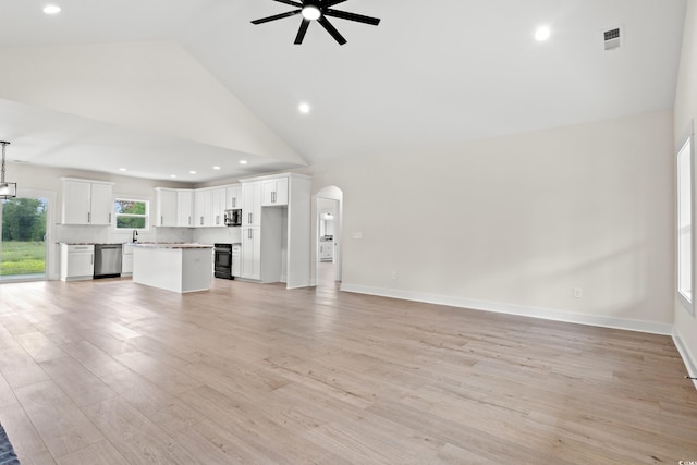 unfurnished living room with ceiling fan, light hardwood / wood-style floors, sink, and high vaulted ceiling