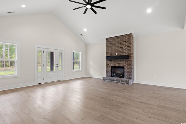 unfurnished living room featuring ceiling fan, high vaulted ceiling, light hardwood / wood-style floors, and a brick fireplace