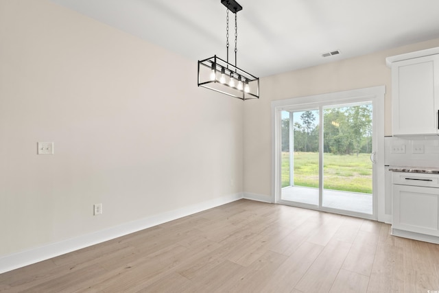 unfurnished dining area with light wood-type flooring and an inviting chandelier