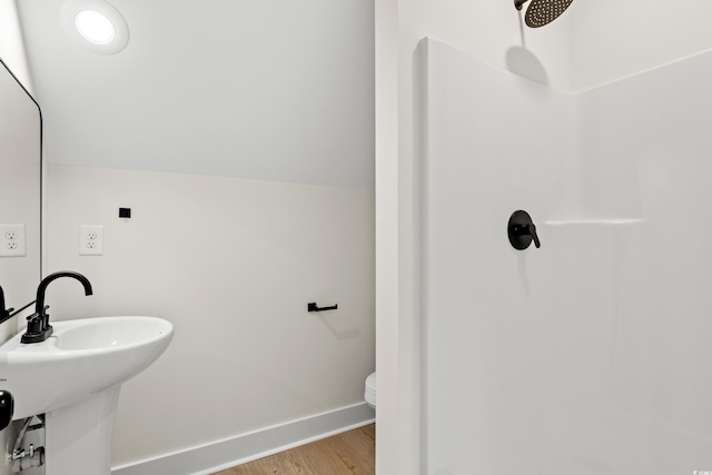 bathroom featuring wood-type flooring, vaulted ceiling, toilet, and sink