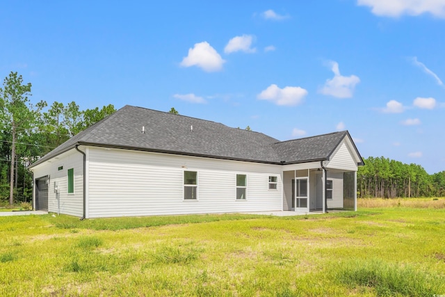 rear view of house with a sunroom, a garage, and a lawn