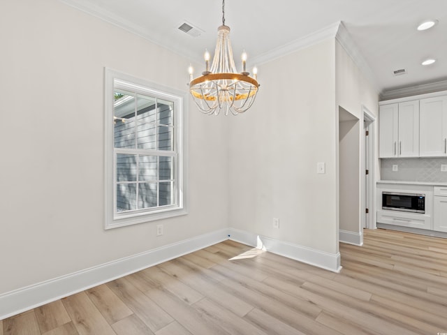 unfurnished dining area with crown molding, light wood-type flooring, and an inviting chandelier