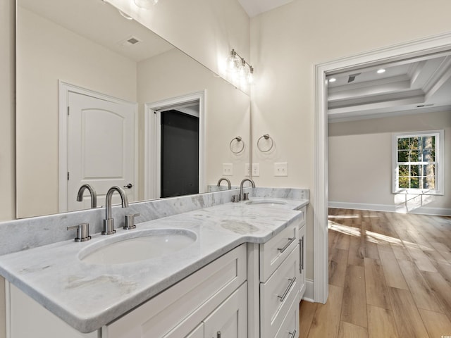 bathroom with hardwood / wood-style flooring, vanity, a raised ceiling, and crown molding