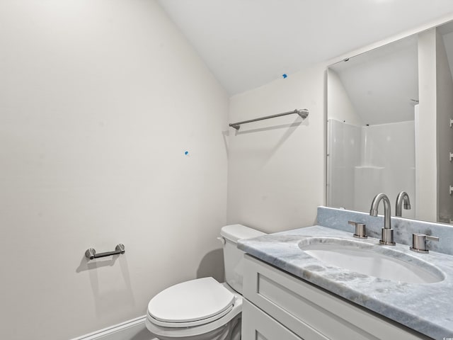 bathroom featuring vanity, vaulted ceiling, and toilet