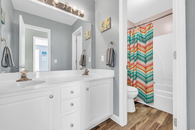 full bathroom with wood-type flooring, toilet, vanity, and shower / tub combo