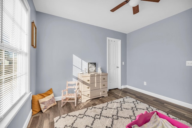 living area featuring ceiling fan, dark wood-type flooring, and a wealth of natural light