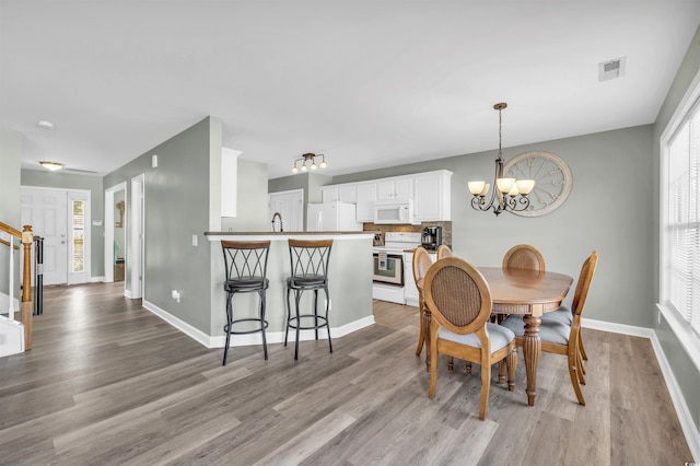 dining space featuring light hardwood / wood-style flooring and a chandelier