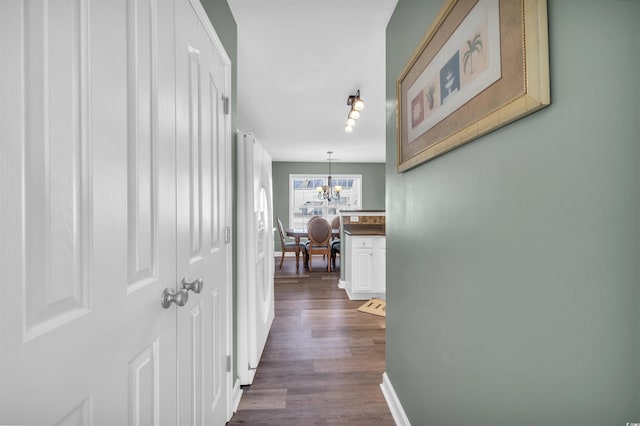 hallway with dark hardwood / wood-style flooring and an inviting chandelier