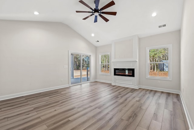 unfurnished living room featuring a wealth of natural light, ceiling fan, light hardwood / wood-style floors, and vaulted ceiling